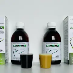 Dwa opakowania AviSalmo Tonic, antybiotyk na drogi oddechowe dla gołębi, obok dwóch kieliszków z płynem.